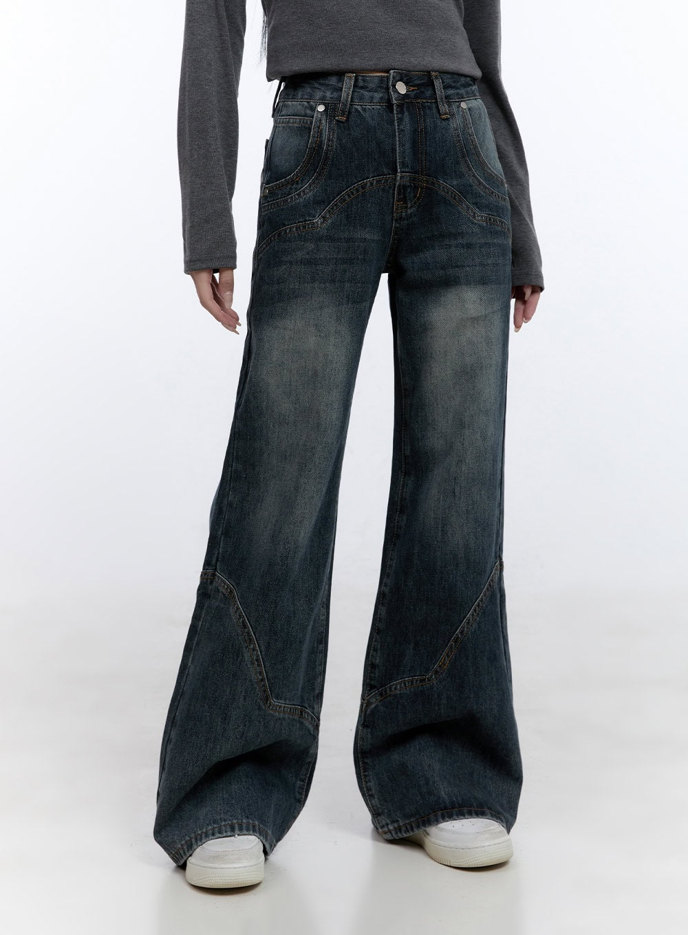 Barbara Washed Wide Leg Jeans CD420 in blue, front close-up on model, washed denim with curved decorative stitch yoke and panel seams, wide leg cotton denim, paired with grey top and white sneakers.