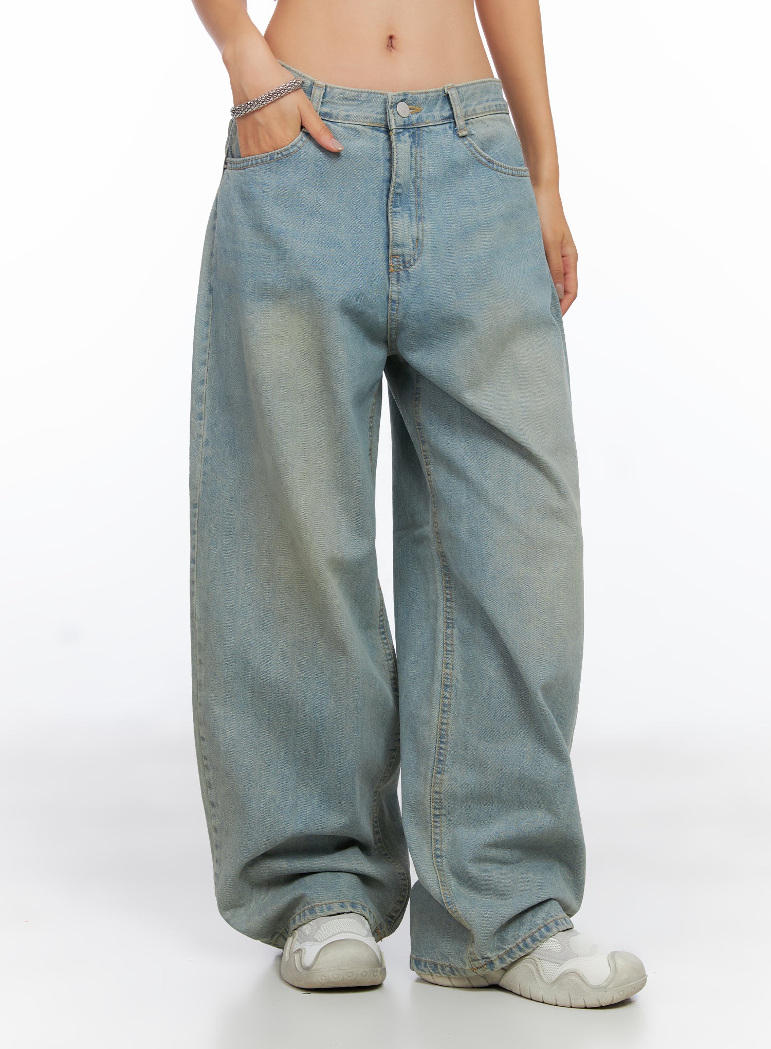 Remi Washed Baggy Jeans CO515 in light blue, front three-quarter view on model, hand in pocket, relaxed washed cotton wide leg with pooled hem over white sneakers.