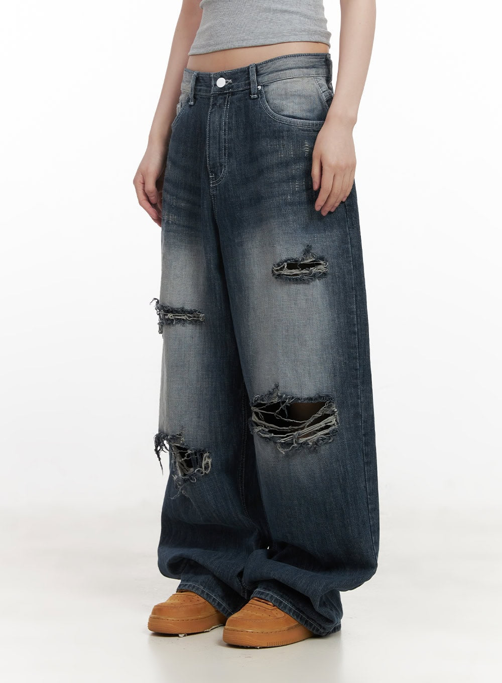 Alison Destroyed Baggy Jeans CJ523 in dark blue, side front shot on model in gray crop top, emphasizing large frayed knee rips, washed cotton denim, and oversized wide-fit leg.