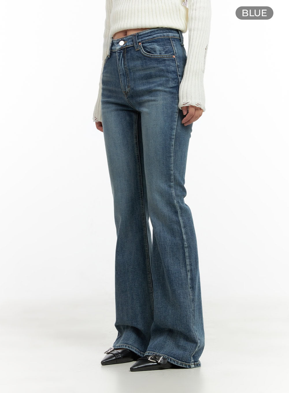 Lila Slim Bootcut Jeans CG422 in blue, angled front three-quarter shot on model, slim fit high-rise washed denim with subtle bootcut flare, paired with white ribbed knit and black buckle boots.