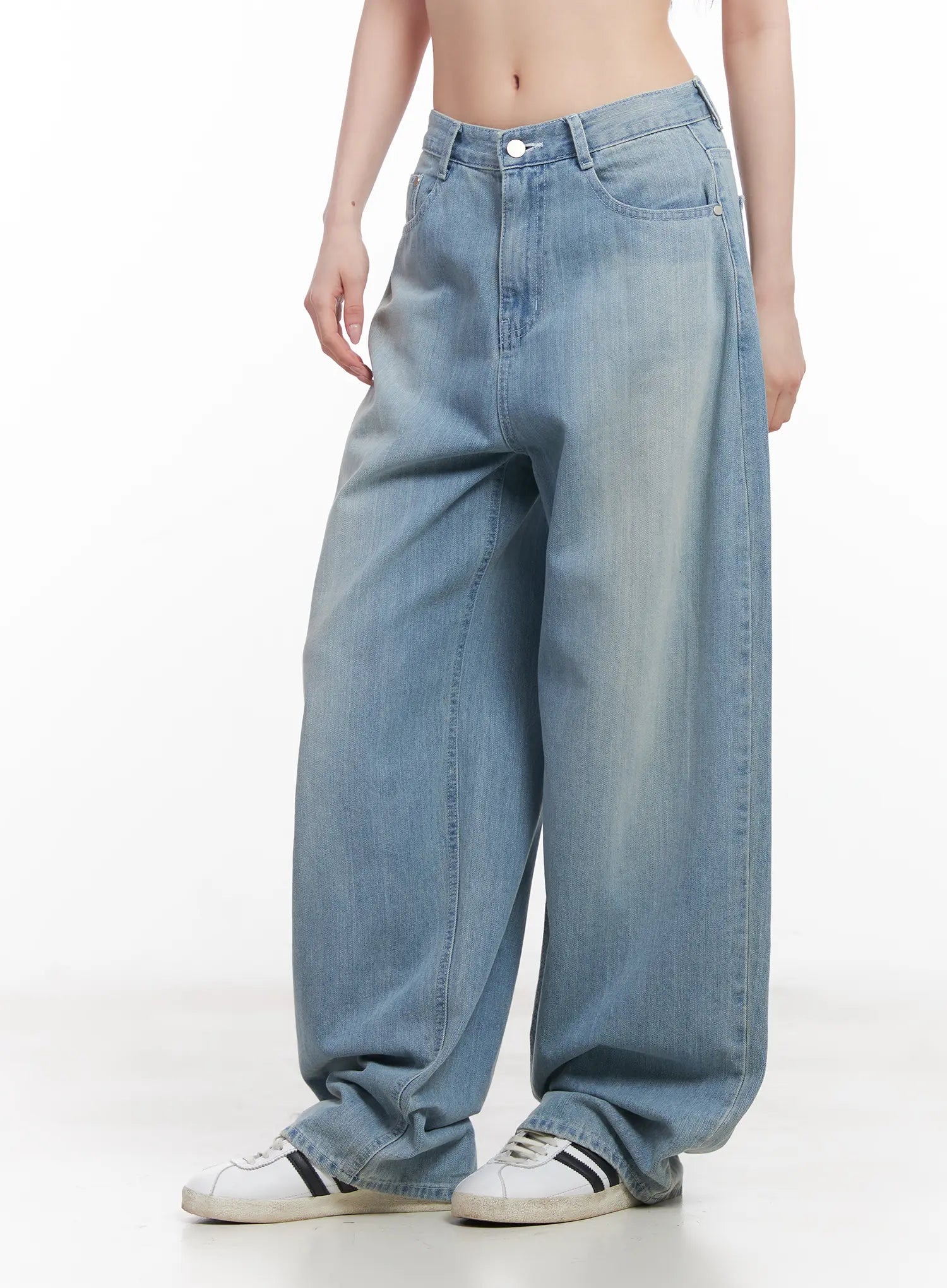 Rose Washed Baggy Summer Denim Jeans CU511 in light blue, angled front side view on model, wide-leg washed cotton denim showing low-rise waistband, roomy thigh, and pooling hem at sneakers.