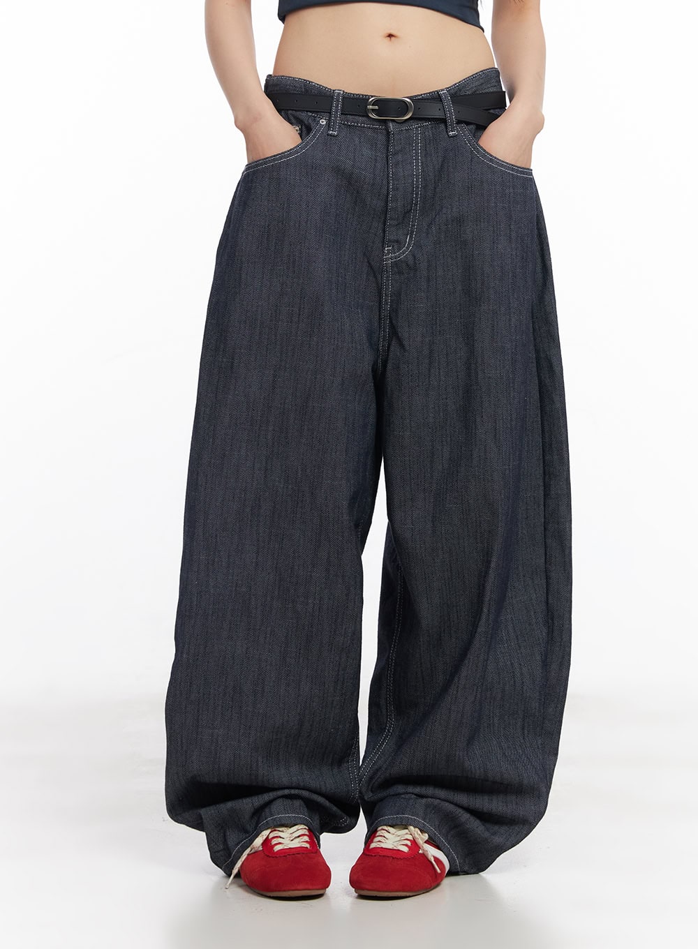 Isabel No-Fade Baggy Jeans CY514 in dark blue, front mid-body shot on model, hands in pockets, low-rise fit with black O-ring belt buckle, ultra-wide cotton denim legs, red sneakers.