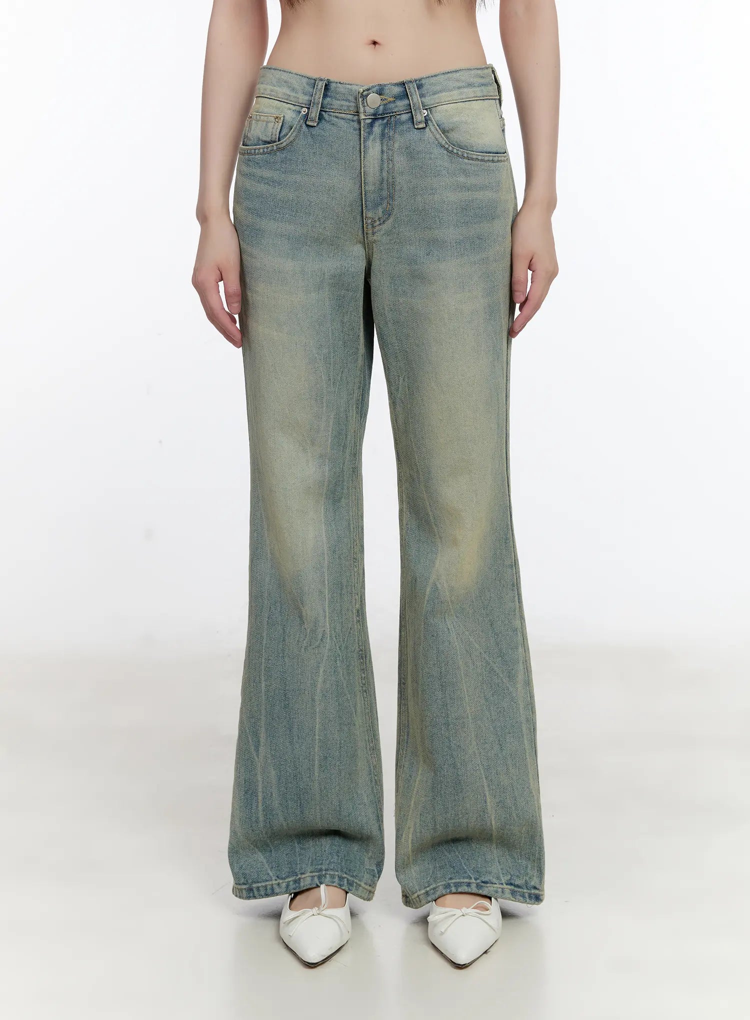 Roa Vintage Blue Flared Denim Jeans CL504 in blue, front waist-to-hem product shot on model, low-rise flared cotton denim with yellow vintage wash, five-pocket styling, white pointed flats.