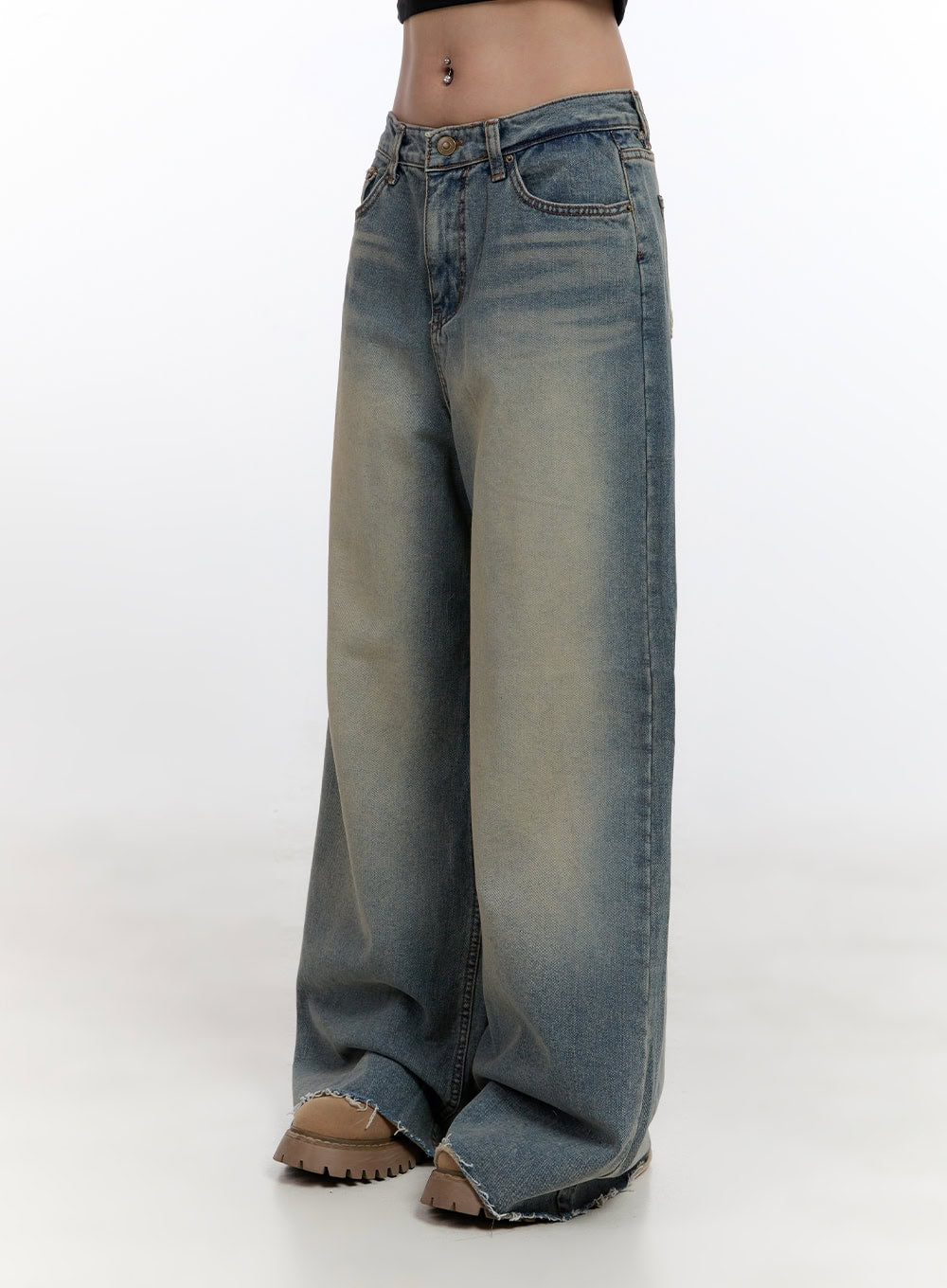 Felicia Cotton Wide Fit Baggy Jeans CN425 in blue, front three-quarter close-up on model, washed cotton denim, low-rise five-pocket styling, yellow-tinted fade wash, raw frayed hem, chunky beige boots.