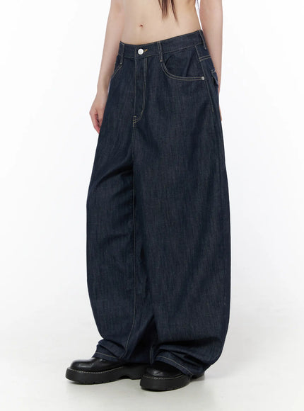 Rowen Baggy Jeans CU519 in dark blue, angled three-quarter front view on model, highlighting balloon-shaped leg curve, coin pocket, contrast stitching, worn with black chunky sole shoes.