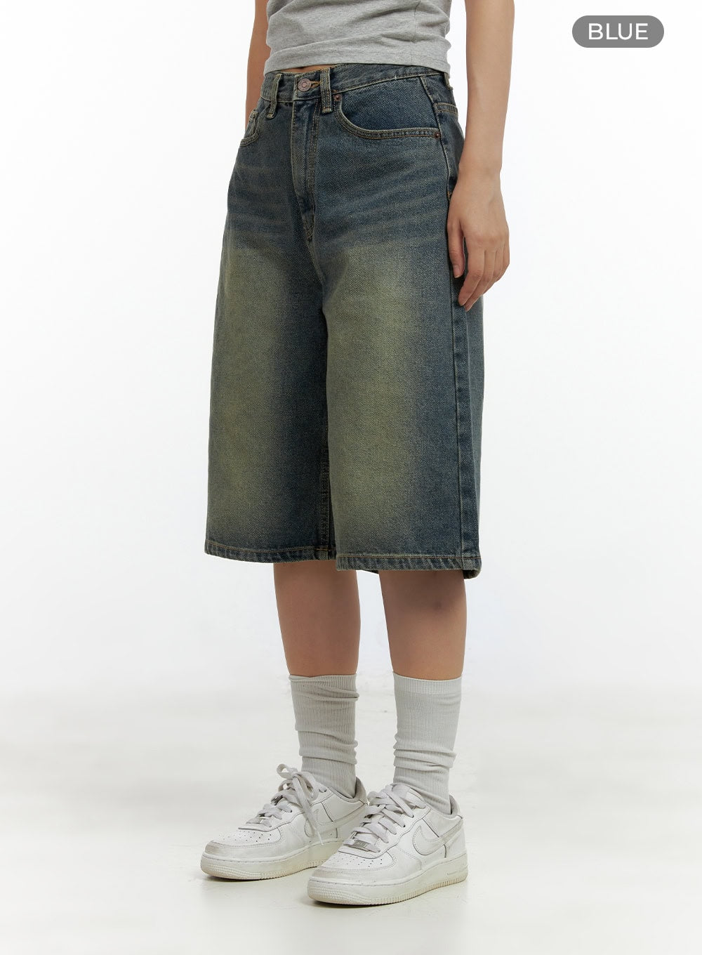 Slim Fit Bermuda Jorts CL410 in blue, angled front-side view on model, wide-leg cotton denim with washed fade detail and midi inseam, styled with white sneakers.