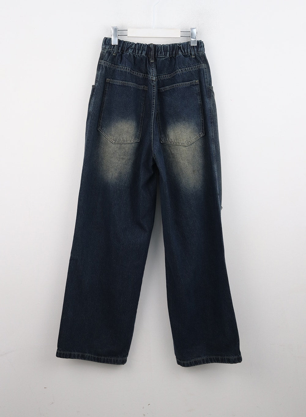 Destroyed Washed Wide Leg Jeans CN324 in dark blue, flat back product shot on hanger, revealing elasticated waistband, oversized back patch pockets with vintage yellow fade highlight, and wide straight hem.