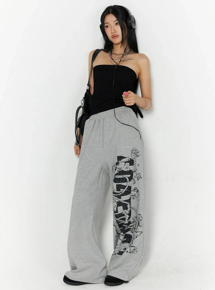 404 Error Graphic Sweatpants IL516 Gray lifestyle front shot on model with headphones black tube top and crossbody bag showing graphic print on leg