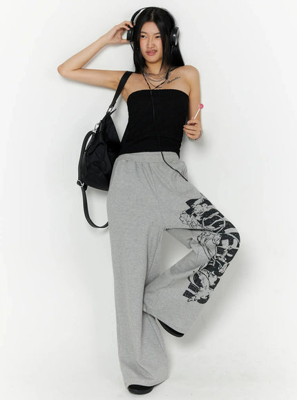 404 Error Graphic Sweatpants IL516 Gray full-body lifestyle shot on model wearing headphones and black tube top holding lollipop with crossbody bag
