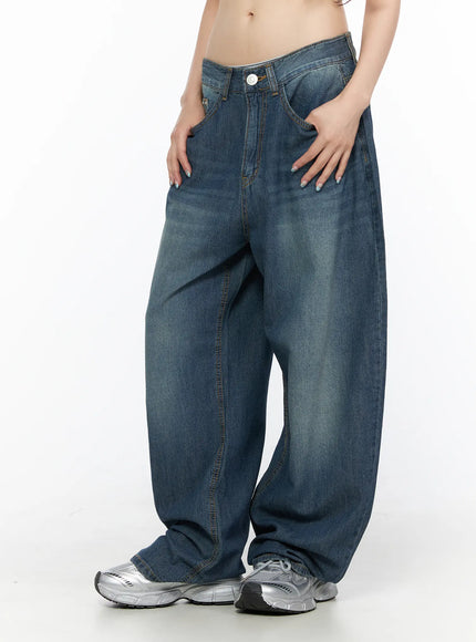 Ace Washed Wide Leg Jeans CL522 Dark blue angled front close-up on model with hands in pockets, showcasing voluminous washed denim leg, center seam, and silver chunky sneakers