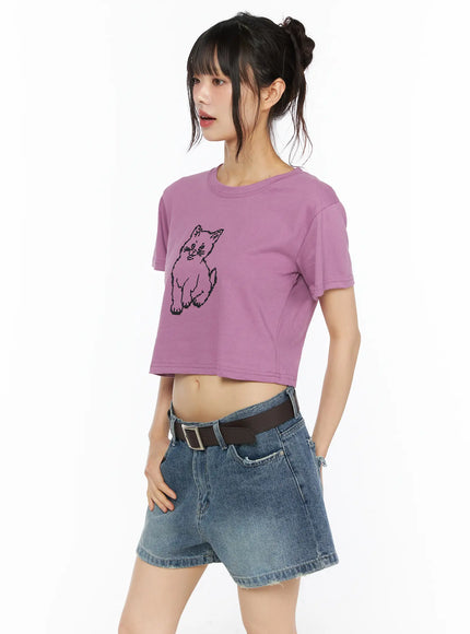 Animal Graphic Crop Tee CU530 Purple three-quarter front view on model with black pixel cat graphic styled with denim shorts and brown belt