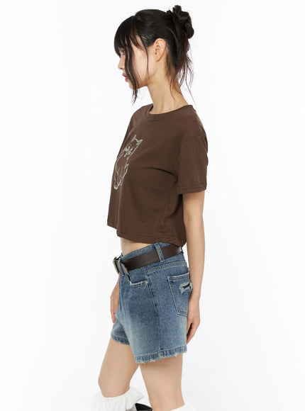 Animal Graphic Crop Tee CU530 Brown side view on model showing cropped hem short sleeves and pixel cat graphic with denim shorts