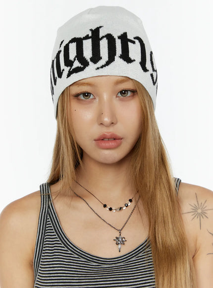 LEWKIN Aspen 1988 beanie IL503 White front close-up on model facing camera wearing knit beanie with black gothic letter jacquard
