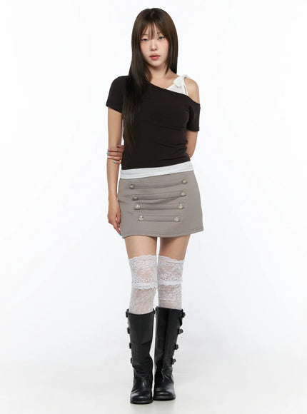 Asymmetric Off-Shoulder Top CL517 Dark brown front full-body shot model standing wearing black top with white bow strap detail and grey mini skirt