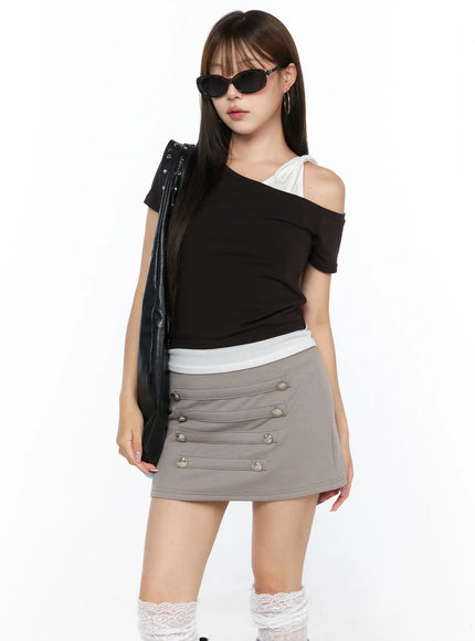 Asymmetric Off-Shoulder Top CL517 Dark brown three-quarter front shot model with sunglasses carrying black bag showing silver button mini skirt and lace socks