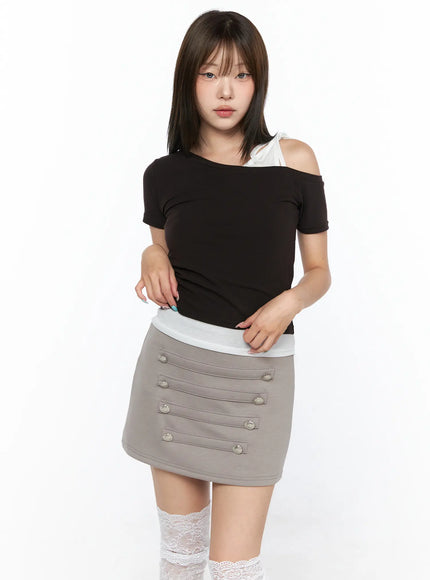 Asymmetric Off-Shoulder Top CL517 Dark brown front shot model standing hands at waist showing silver button detail on grey mini skirt with lace socks
