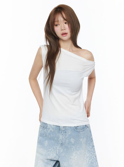 Asymmetric One-Shoulder Top IU525 White front half-body shot on model arms at sides showing asymmetric neckline and soft knit fabric with denim shorts