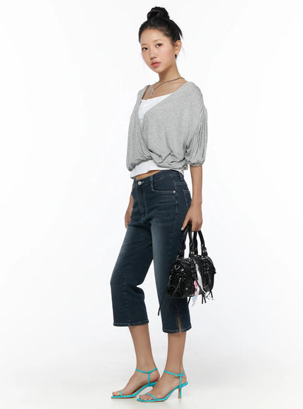 Axel Slit Capri Jeans CL510 dark blue three-quarter side shot on model wearing gray wrap top, holding bag, showing slit hem detail