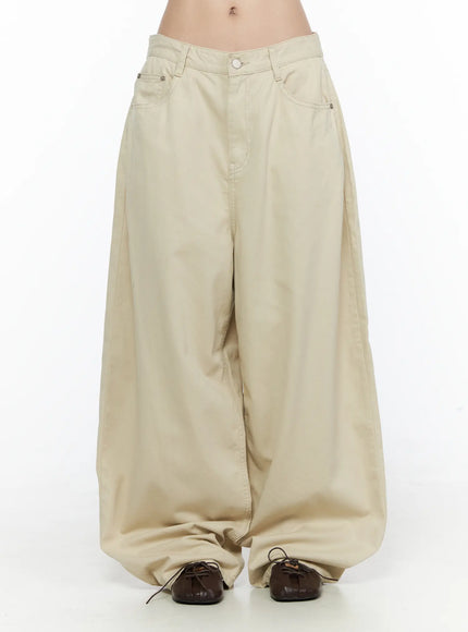 Back Pocket Wide Leg Pants CL524 Beige front close-up on model showing low-rise waistband, silver button closure, front pockets, and voluminous wide leg