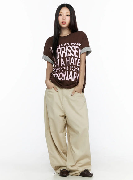 Back Pocket Wide Leg Pants CL524 Beige front full-length on model styled with brown graphic tee, hands in pockets, standing pose showing full leg volume