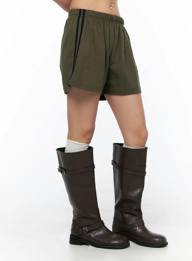 Banded Cotton Shorts CU524 Dark green close-up side shot on model showing elastic waistband and black side stripe detail with boots