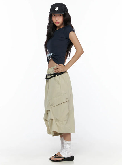 Basic Crewneck Tee CL510 Dark blue side shot on model styled with beige cargo midi skirt and cap, showing side bow charm detail and cropped hem