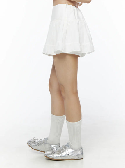 Basic Frill Flare Mini Skirt IU525 White side model shot showing flared tiered pleated silhouette with back zipper detail paired with white socks and silver shoes
