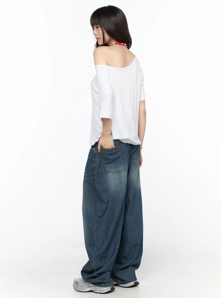 Basic Loose Fit Asymmetric Tee CL522 White back-angle shot on model revealing bare shoulder asymmetric neckline and relaxed silhouette styled with wide-leg jeans