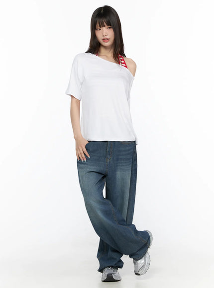 Basic Loose Fit Asymmetric Tee CL522 White full-body front shot on model with asymmetric cold-shoulder neckline and red striped bra strap detail with wide-leg jeans