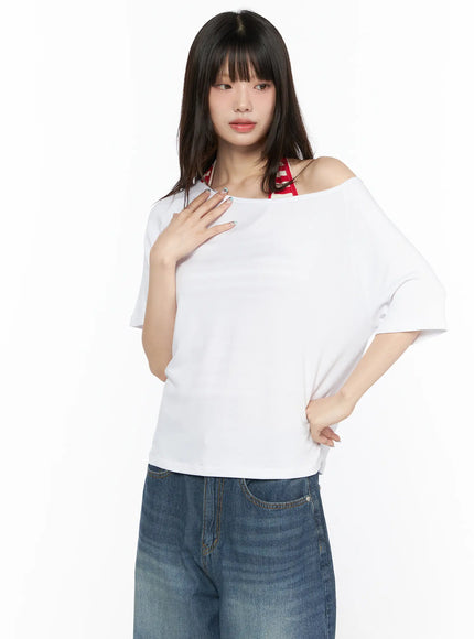 Basic Loose Fit Asymmetric Tee CL522 White front shot on model with hand on chest highlighting asymmetric off-shoulder neckline and red striped inner strap accent