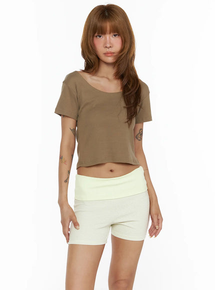 Basic Off-Shoulder Crop Tee CL503 Dark beige front shot on model straight pose showing wide scoop neckline short sleeves and crop length paired with cream ribbed mini shorts