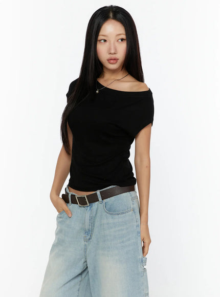 Basic One-Shoulder Top CU529 Black angled front view on model with hands in pockets, fitted asymmetric one-shoulder crop silhouette styled with light denim