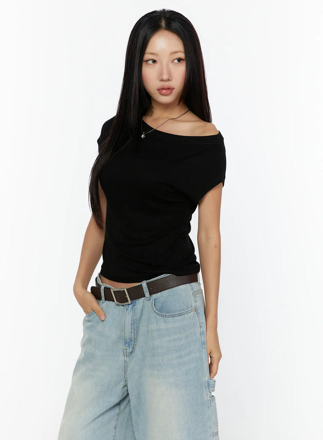 Basic One-Shoulder Top CU529 Black angled front view on model with hands in pockets, fitted asymmetric one-shoulder crop silhouette styled with light denim