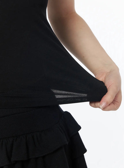 Basic Padded Cami Top IU525 Black close-up detail shot on model showing waistband stretch fabric and sheer mesh panel at hip transition to ruffle skirt