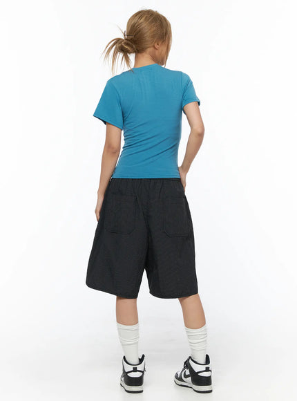 Basic Short Sleeve Top CU523 Blue S/M — back full-body shot, model standing showing rear of fitted blue crop tee with black shorts and sneakers