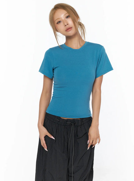 Basic Short Sleeve Top CU523 Blue S/M — front upper-body shot, model looking forward hands relaxed at sides, fitted blue tee with black wide-leg trousers