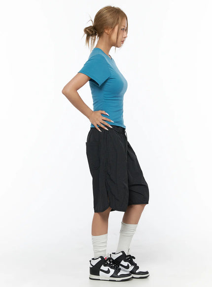 Basic Short Sleeve Top CU523 Blue S/M — side full-body shot, model hand on hip facing left, fitted blue tee with black wide shorts and sneakers