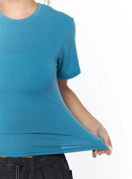 Basic Short Sleeve Top CU523 Blue — detail close-up shot, model stretching fabric hem to show stretch and fine knit texture of blue crop tee
