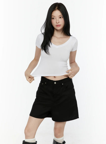 Basic V-Neck Crop Top IL506 White front view on model pulling hem to show cropped length and stretchy ribbed texture with black shorts