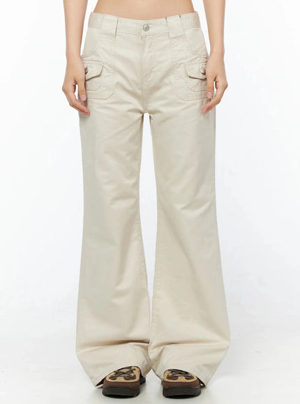 LEWKIN Bootcut Cargo Pants IL516 Light beige front view on model, cropped frame showing snap-button cargo pockets, low-rise waistband, cotton twill flare leg, chunky sneakers