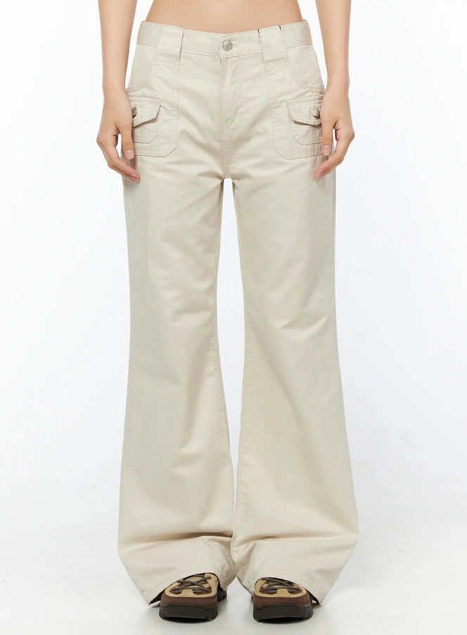 LEWKIN Bootcut Cargo Pants IL516 Light beige front view on model, cropped frame showing snap-button cargo pockets, low-rise waistband, cotton twill flare leg, chunky sneakers