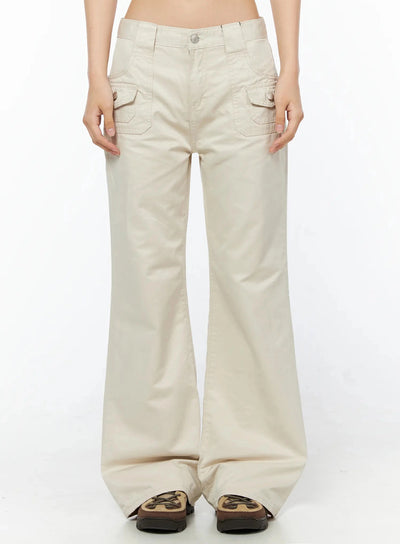 LEWKIN Bootcut Cargo Pants IL516 Light beige front view on model, cropped frame showing snap-button cargo pockets, low-rise waistband, cotton twill flare leg, chunky sneakers