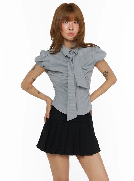 Bow Detail Puff Blouse CL503 Gray front shot on model with hands on hips, puff sleeves, long bow tie at neck, fitted pinstripe body, paired with black pleated mini skirt