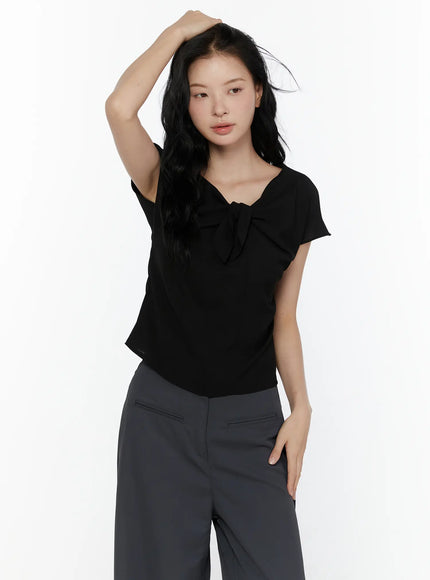 Bow Tie Cap Sleeve Blouse CL520 Black angled front shot on model hand raised showing bow tie neckline detail and flutter cap sleeves