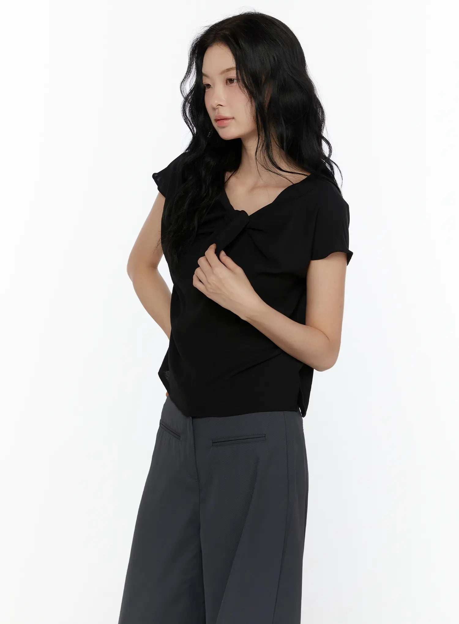 Bow Tie Cap Sleeve Blouse CL520 Black side shot on model hand on chest highlighting fitted silhouette bow detail and flutter cap sleeve
