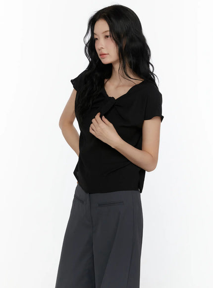 Bow Tie Cap Sleeve Blouse CL520 Black side shot on model hand on chest highlighting fitted silhouette bow detail and flutter cap sleeve