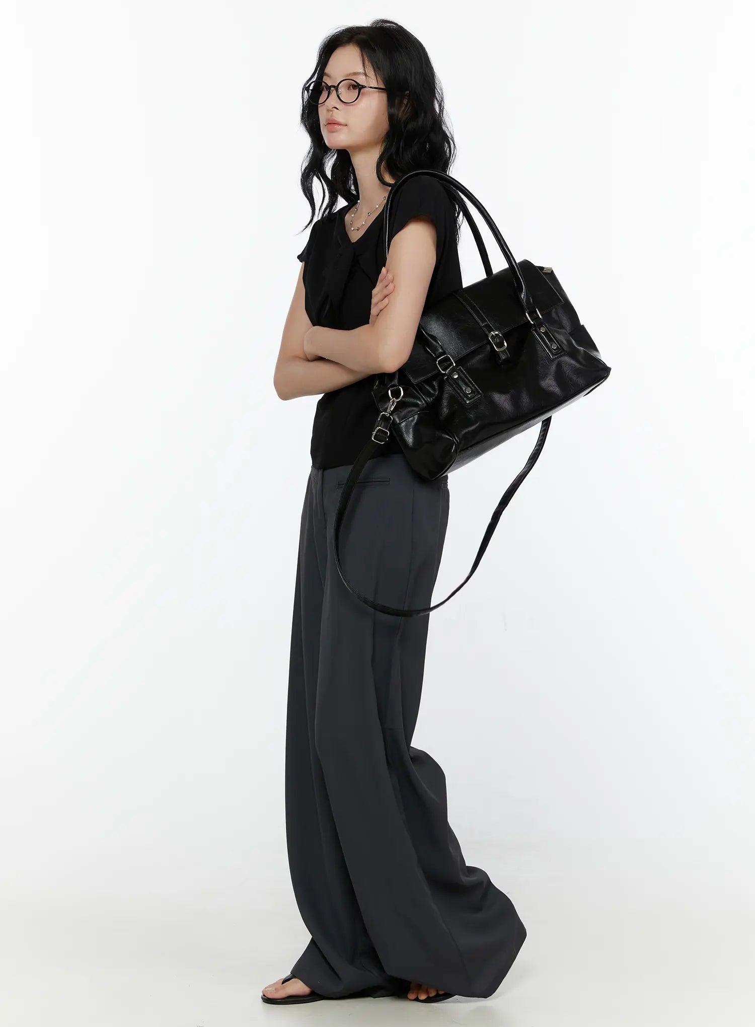 Bow Tie Cap Sleeve Blouse CL520 Black side full-body shot on model arms crossed carrying large black leather tote with grey wide-leg trousers