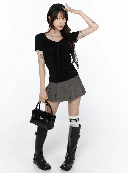 LEWKIN Bow Top IL506 Black S/M front full-body shot on model styled with gray pleated mini skirt, knee-high boots, white stripe socks, and black handbag