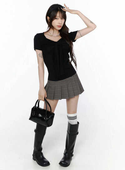 LEWKIN Bow Top IL506 Black S/M front full-body shot on model styled with gray pleated mini skirt, knee-high boots, white stripe socks, and black handbag