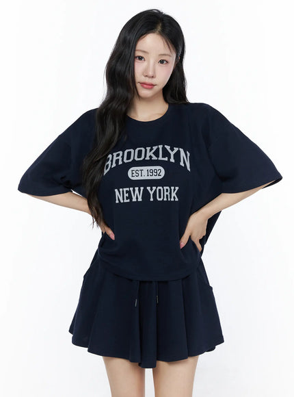 Brooklyn Grahic Tee & Mini Skort Set IU525 Dark blue front view on model hands on hips showing Brooklyn New York EST.1992 graphic cropped tee and skort